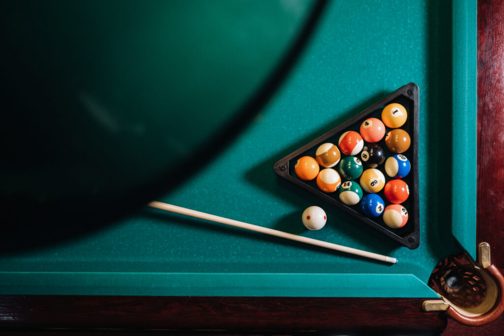 billiards ball on a pool table beside a billiard stick
