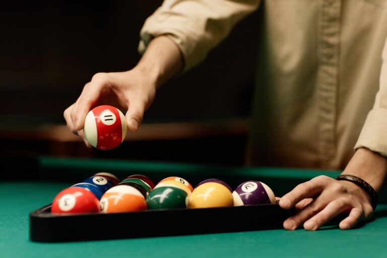 a man putting in a billiard ball in a pool table