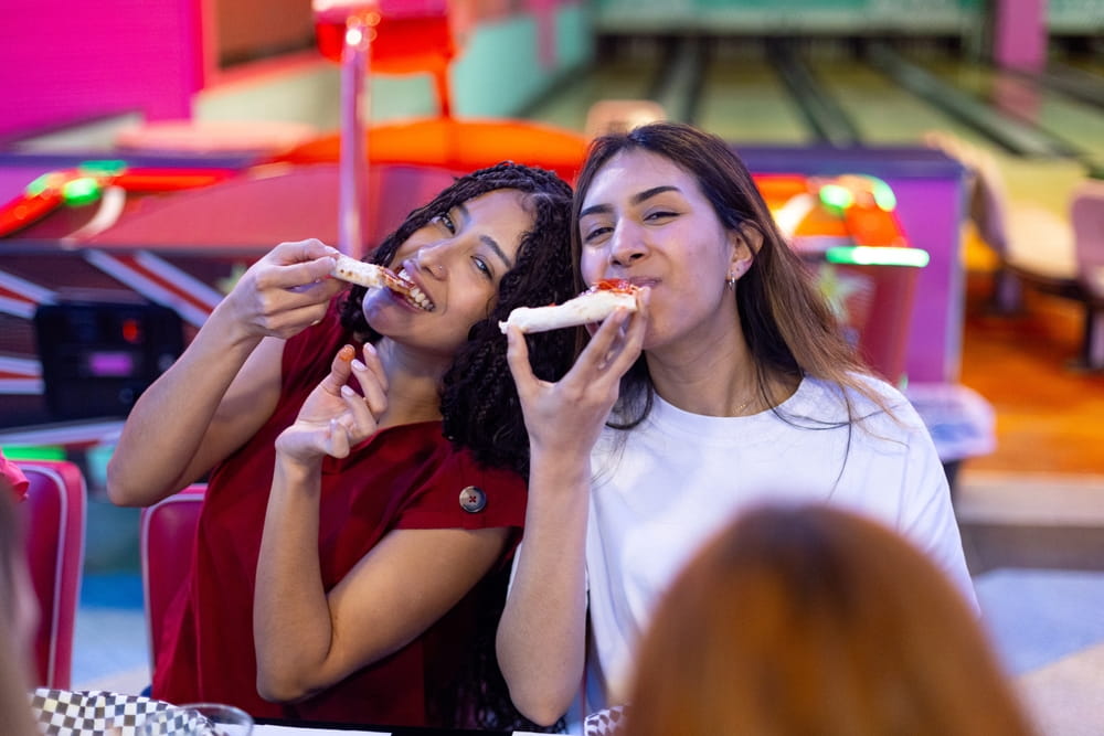 two friends eating some snacks at the bowling alley